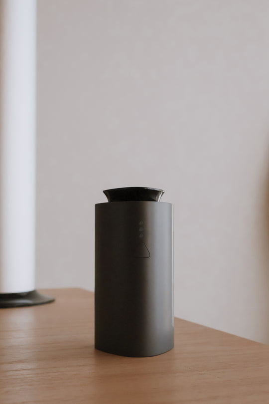 Air Luxe Mini Diffuser and Portable Cold-Air Scent System in matte black on a wooden table, showcasing its sleek and minimalist luxury design by Chateau Essence.
