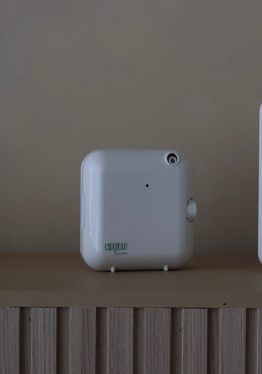 Chateau Aura Diffuser and Compact Cold-Air Scent System displayed on a wooden shelf with neutral background – luxury small-space diffuser by Chateau Essence.