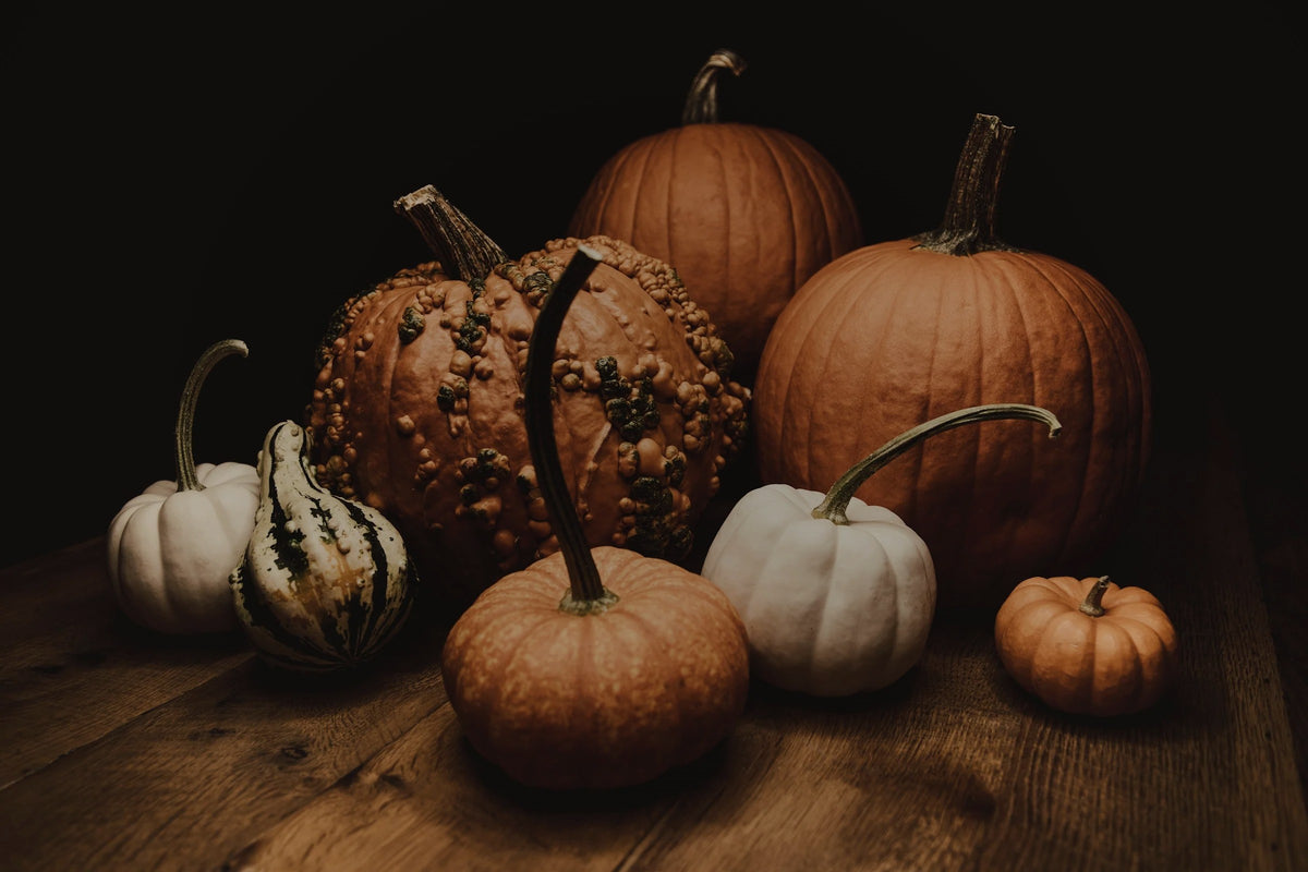 Heirloom pumpkins and gourds on a dark wooden table – Chateau Essence Holiday Collection fall fragrances